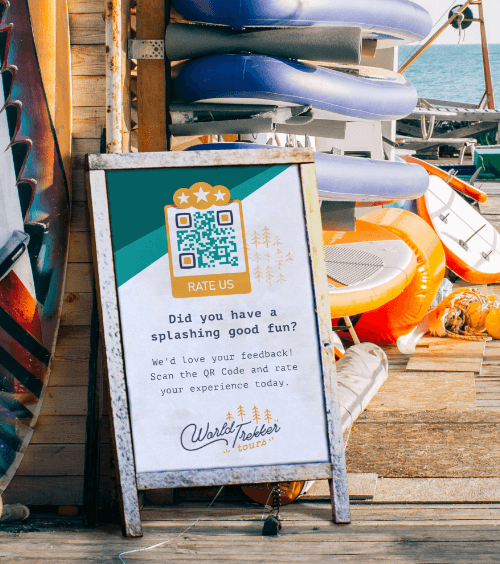 Un espositore pubblicitario in un ufficio prenotazioni di paddleboarding con un QR Code che invita i clienti a valutare le loro esperienze