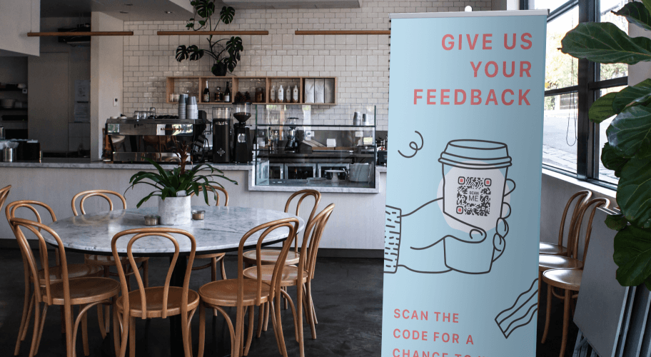 Pubblicità con un QR code in una caffetteria che chiede alle persone la loro opinione.